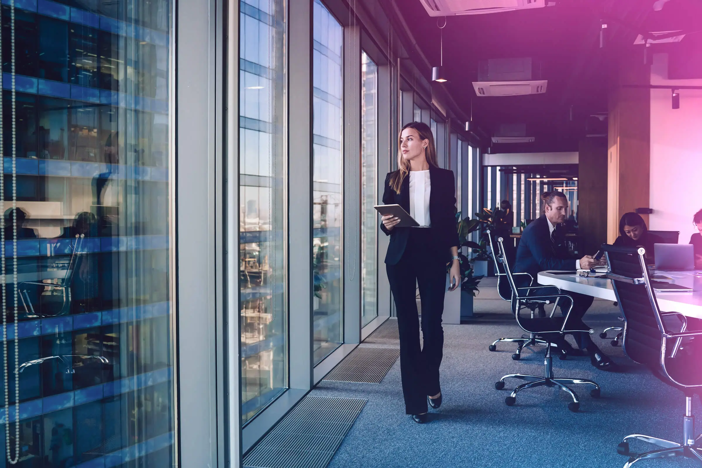 A woman in a suit walks through an office.